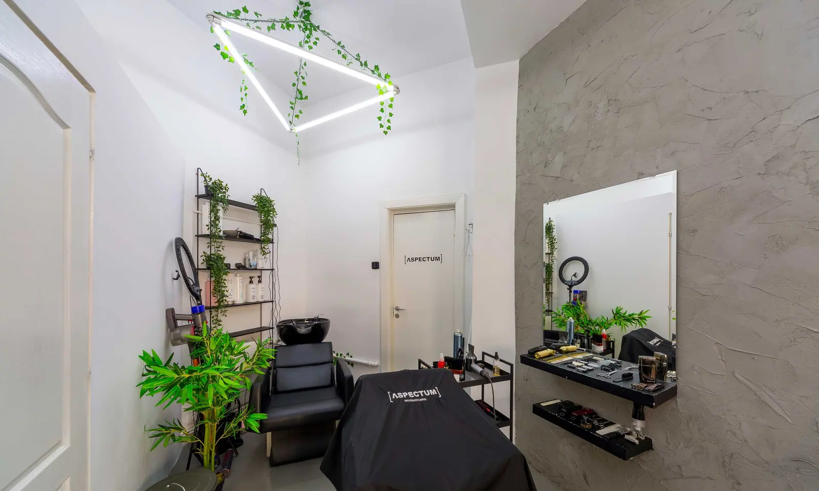 Salonul ΛSPECTUM cu liniile de neon geometrice de pe tavan și scaunul de spălat